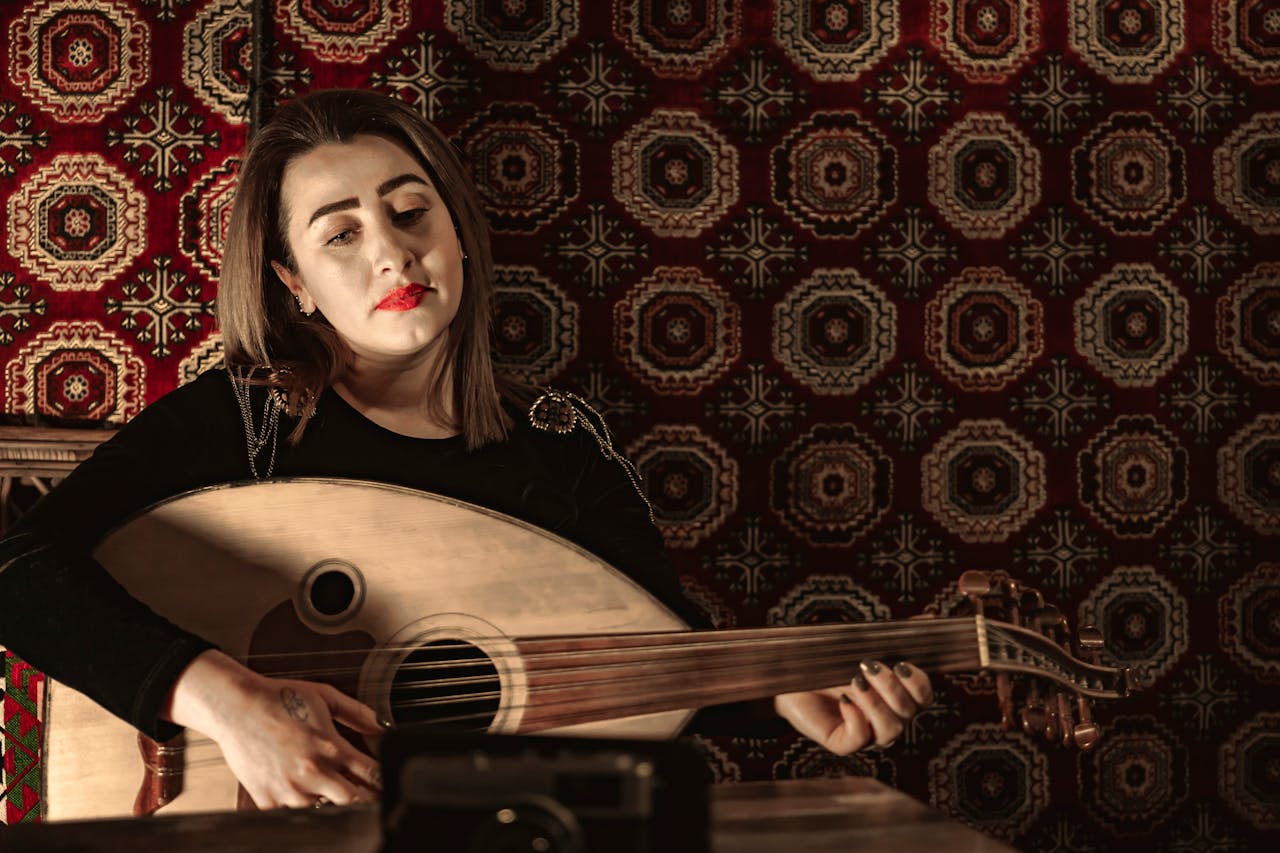 about-04 A young woman plays the oud in a traditional setting with patterned textiles. Middle Eastern music scene.