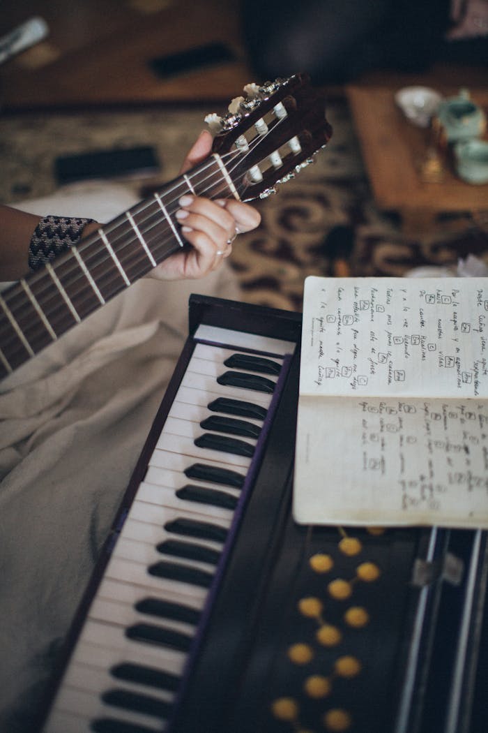 Close-up view of a guitar and keyboard with sheet music, capturing a cozy indoor music session.